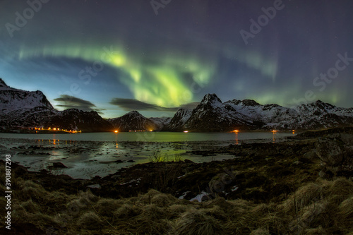 Bild auf Leinwand panoramica de aurora boreal entre montañas frente a un lago
