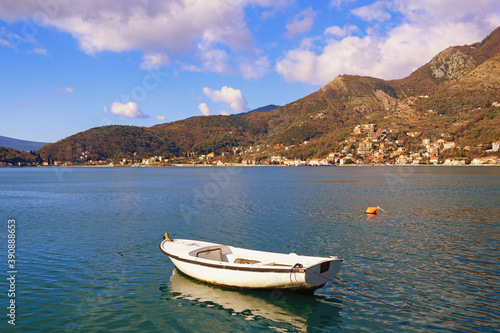 Beautiful Mediterranean landscape on sunny winter day. Montenegro, Adriatic Sea. View of Kotor Bay and fishing boat on water. Kamenary town in distance