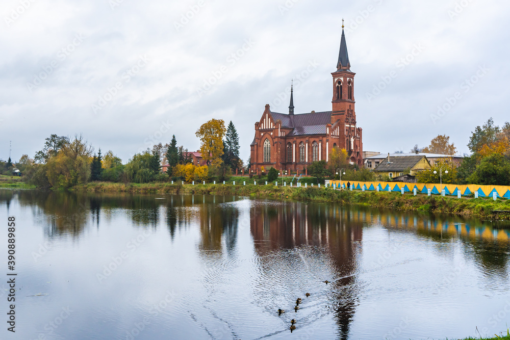 Red Catholic Church with Autumn Trees and Pond