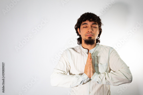 Young Hispanic man wearing casual clothes on a white background meditating quietly with his eyes closed © Antonio Tanaka