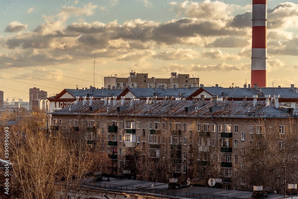 Roofs of houses with chimneys lit by the setting sun. An inspiring cityscape.