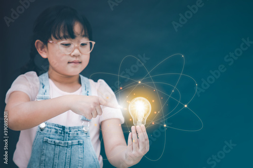 Asian Little girl holding the light bulb and touch in graph Screen Icon of media screen,Technology Process System Business,E-learning Education Internet Technology conceptc photo