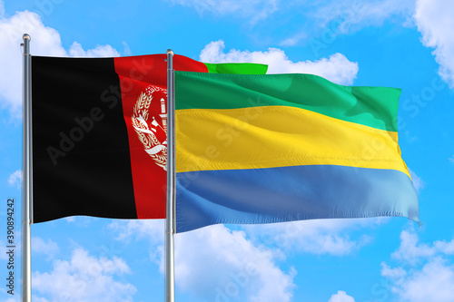 Gabon and Afghanistan national flag waving in the wind on a deep blue sky together. High quality fabric. International relations concept.