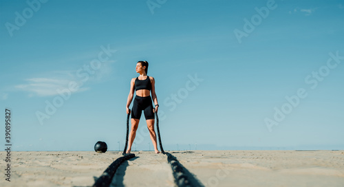 Tablou pe pânză Fit and toned sportswoman working out in functional training gym at the beach -