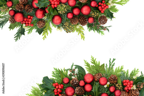 Traditional Christmas border with red baubles & winter flora of holly, ivy, mistletoe, pine cones & cedar cypress fir leaves. Decorative arrangement for the festive season & New Year. Copy space.