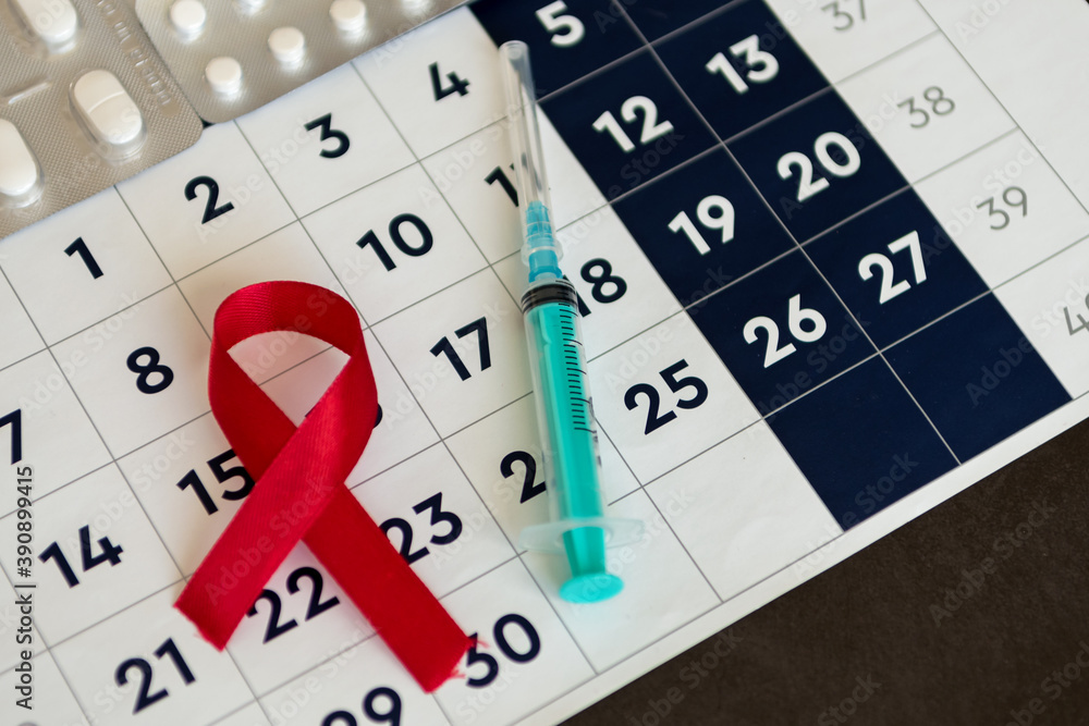 World AIDS Day. Red and calendar on light wooden backgroundworld AIDS day. Red ribbon, medical syringe, and calendar. Concept of health and medicine. World AIDS Day. Red and calendar on light wooden backgroundworld AIDS day. Red ribbon, medical syringe, and calendar. Concept of health and medicine.
