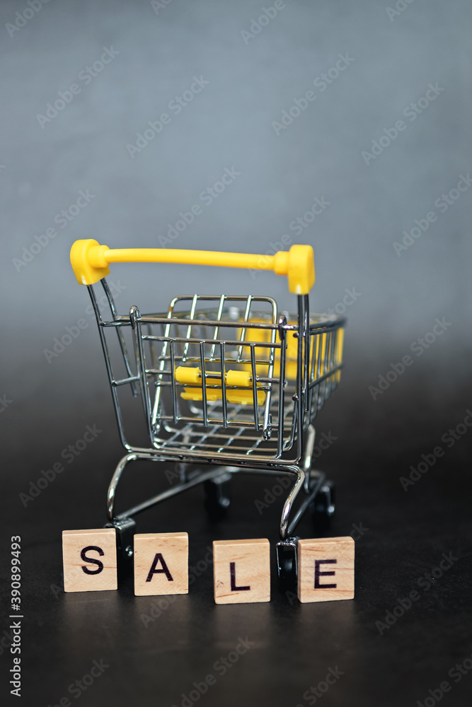Season of sales in online stores. Cart and sales word on dark blue background. Creative idea for a sale, promotion, or concept for cyber Monday or black Friday. Selective focus.