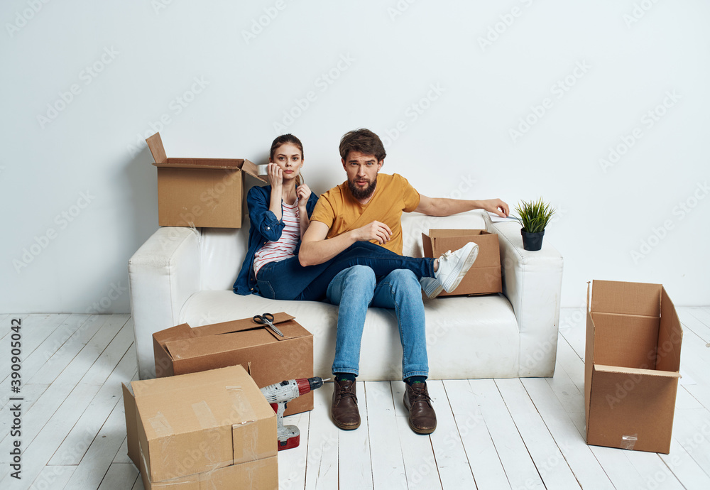 Married couple on a white sofa in the room interior with boxes of communication things Married couple on a white sofa in the room interior with boxes of communication things