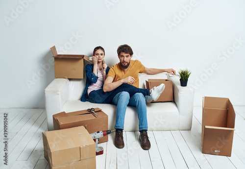 Married couple on a white sofa in the room interior with boxes of communication things © SHOTPRIME STUDIO