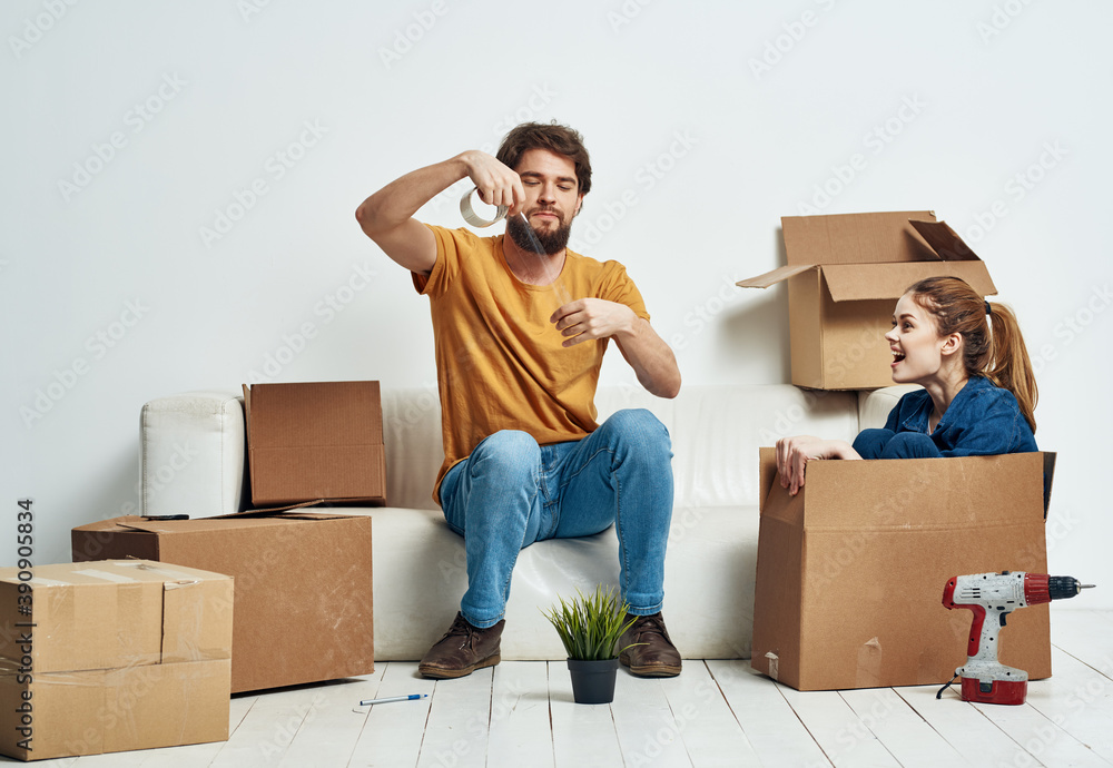 Man and woman boxes with things white sofa interior moving room Man and woman boxes with things white sofa interior moving room