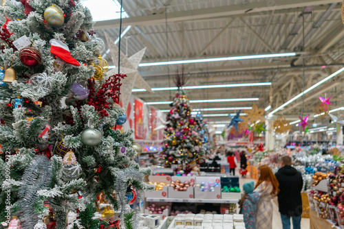 Blurred Christmas supermarket. Sale of festive Christmas accessories and trees in a retail store. Blurred background in the store. Selective focus. photo