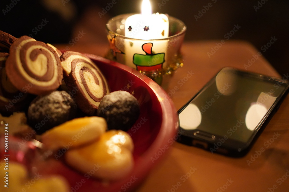 Black cellphone lying offline on a wooden table near candlelight on christmas eve. Black cellphone lying offline on a wooden table near candlelight on christmas eve.