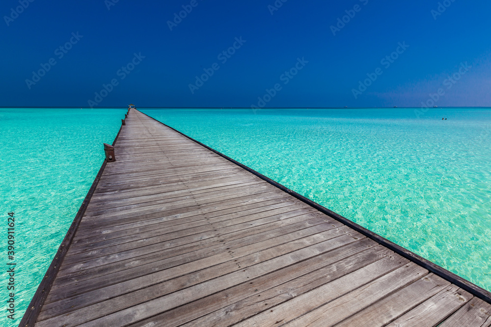 Obraz premium Jetty over atoll and a tropical resort island in Maldives