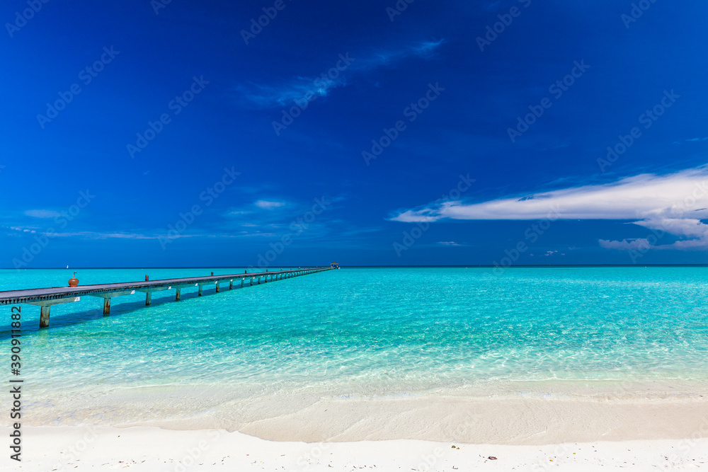 Jetty over atoll and a tropical resort island in Maldives Jetty over atoll and a tropical resort island in Maldives
