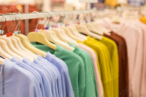 Hangers with jumpers, sweatshirts and thin one-tone colors in a clothing store