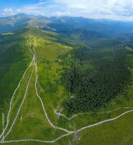 Aerial drone view over the green alpine grasslands of Parang Massif. The peaks are surrounded by numerous wild spruce forests. photo