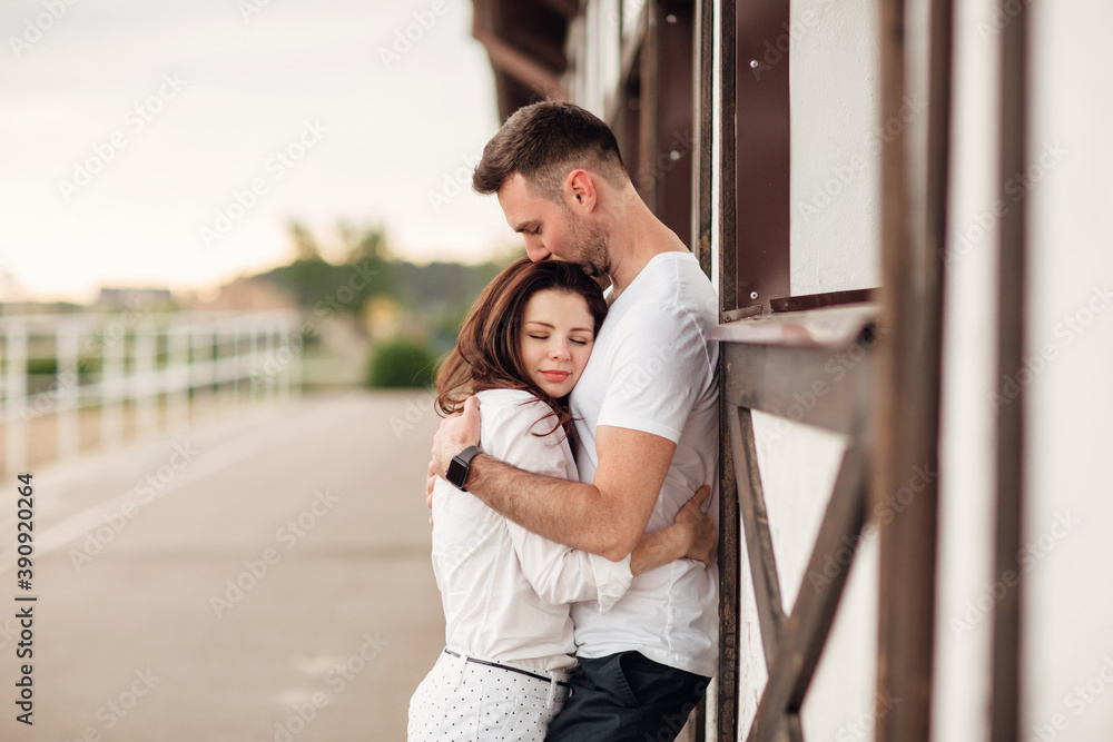 happy young man and woman having fun outdoors on a warm summer day. couple is hugging near horse rancho