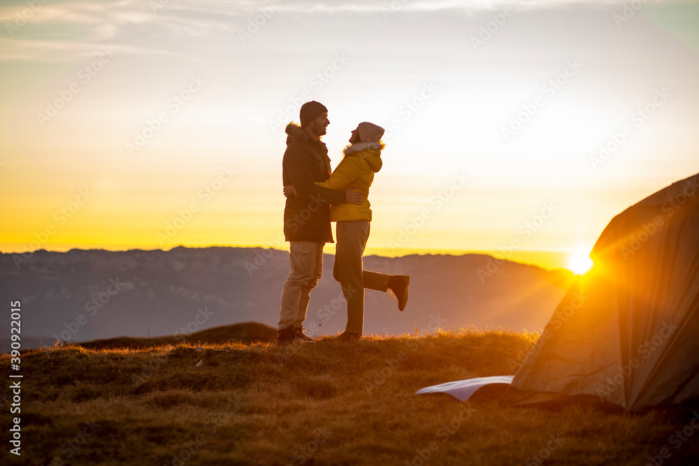 Happy couple hugging and kissing at sunset with an amazing mountain view.
