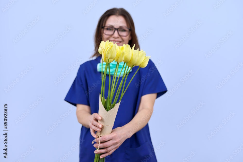 Bouquet of tulip flowers in hands of female doctor with removed protective medical mask Bouquet of tulip flowers in hands of female doctor with removed protective medical mask
