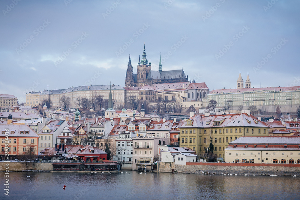Panoramic view of Prague Castle and Vltava River in winter snow lies on red tiled roofs, Picturesque landscape with Cathedral of St. Vitus and royal palace, Prague, Czech Republic