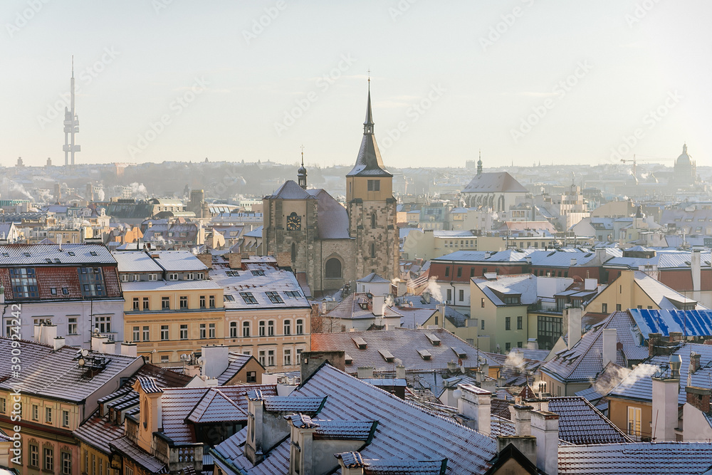 Panoramic view of Prague red tiled roofs with snow at sunny winter day, view from Old Town Bridge Tower to Church of St. Jiljí and Zizkov television tower, Prague, Czech Republic