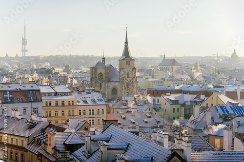 Panoramic view of Prague red tiled roofs with snow at sunny winter day, view from Old Town Bridge Tower to Church of St. Jiljí and Zizkov television tower, Prague, Czech Republic © AnnaRudnitskaya