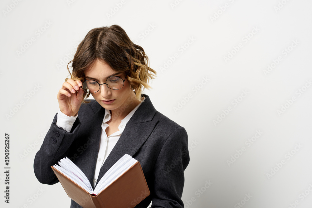 Woman at work with book in hand light background classic suit glasses head Woman at work with book in hand light background classic suit glasses head