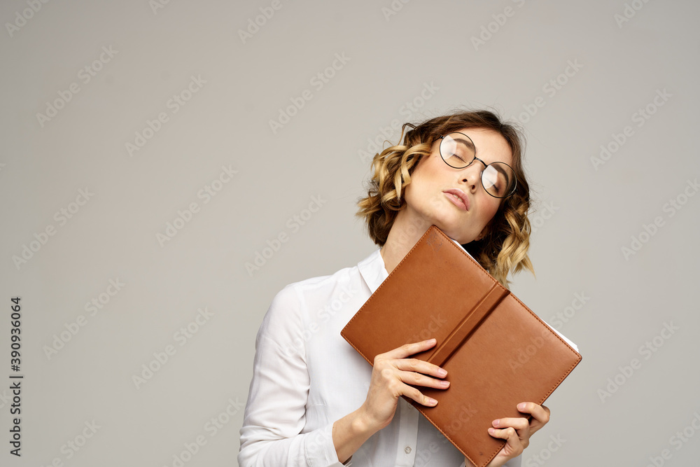 Business woman with notepad and glasses on a light background hairstyle success emotions Business woman with notepad and glasses on a light background hairstyle success emotions