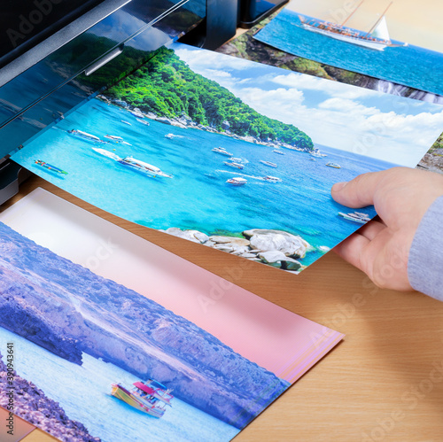 Photographer pulls out a photo printed on a photo printer.