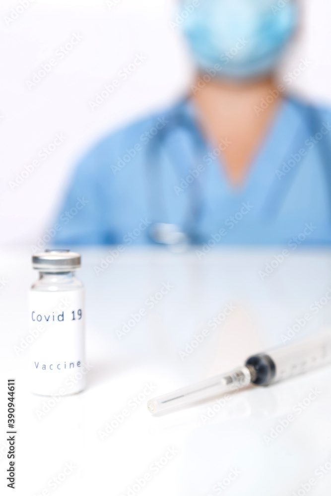 On the table lies a vaccine prevention of the virus and a syringe in the background a doctor in blur. On the table lies a vaccine prevention of the virus and a syringe in the background a doctor in blur.