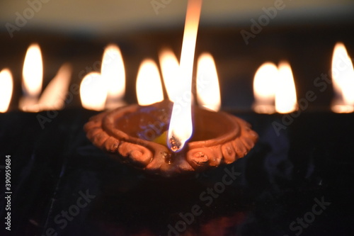 Clay Diya or Oil Lamp lits during the Diwali night. Traditional Diyas lit on gold and black background