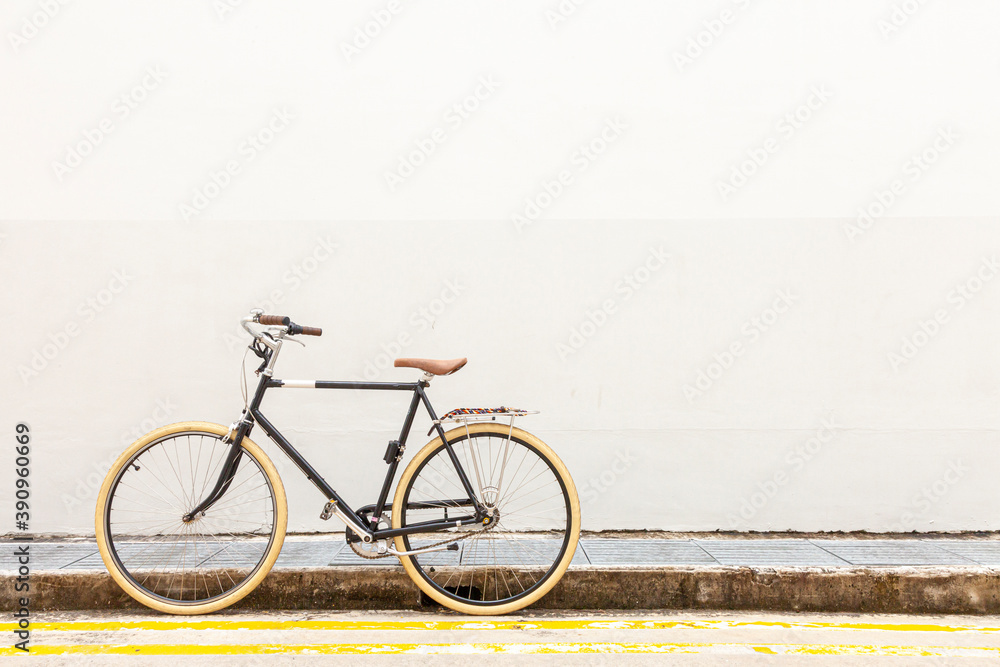 bicycle on the street. Black Vintage Hipster Bicycle With White Tires On A Quiet Street, By A White Wall