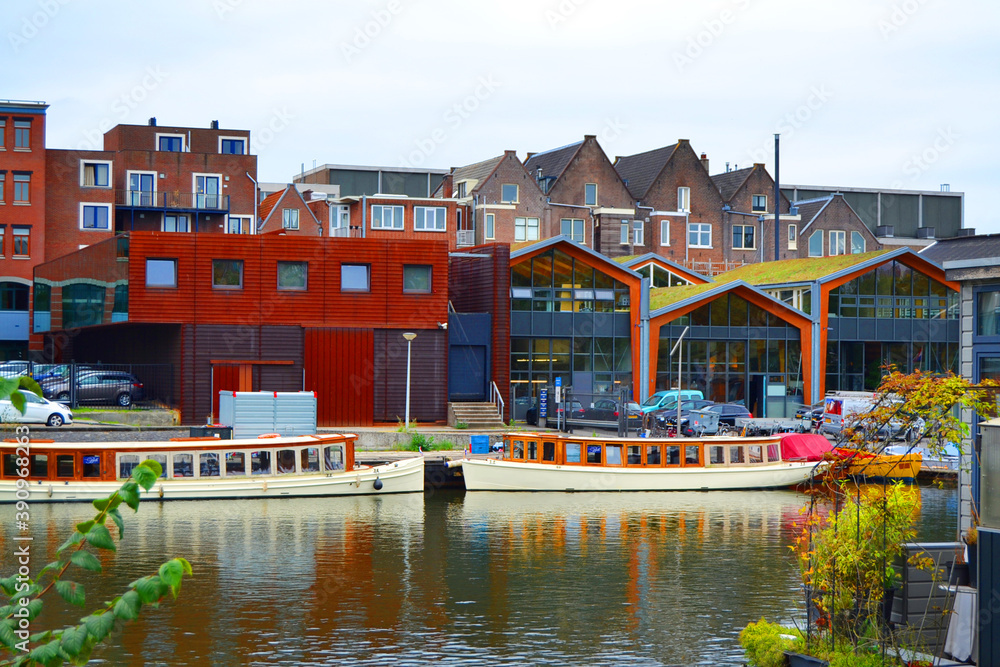 Amstel river, boats and modern architecture in Amsterdam city, The Netherlands. 