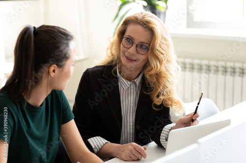 Mentoring on workplace. Friendly capable mature businesswoman worker employee teaching training younger woman colleague intern trainee, explaining task, proposing new idea, helping in work at project