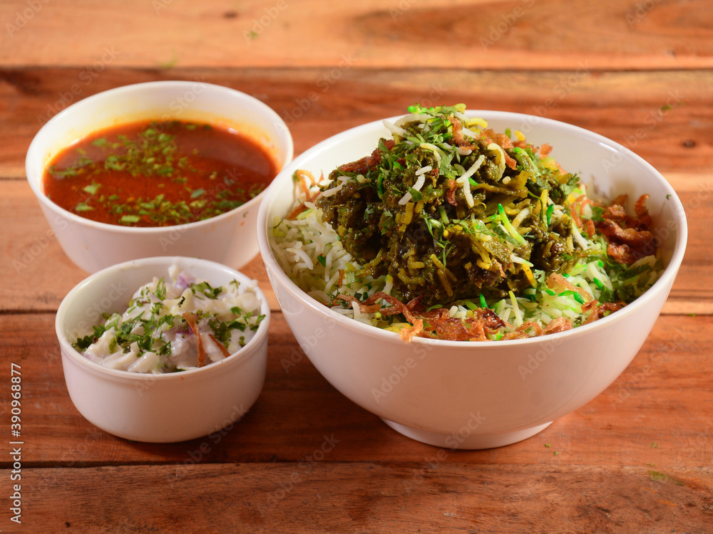 Traditional Hyderabadi Chicken dum Biryani made of Basmati rice cooked with masala spices, served with Onion raita and Salan, selective focus