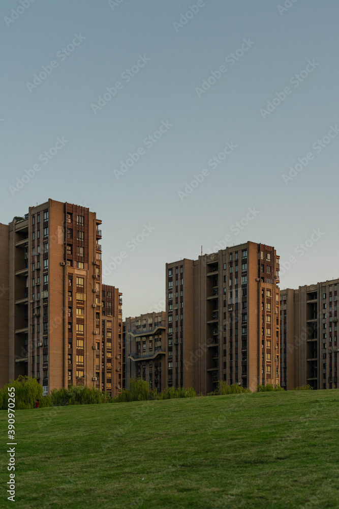 Residential buildings with green grass in front at sunset.