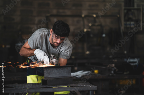 A mechanic wearing safety equipment and operating angle grinder - Metal factory - Industry concept