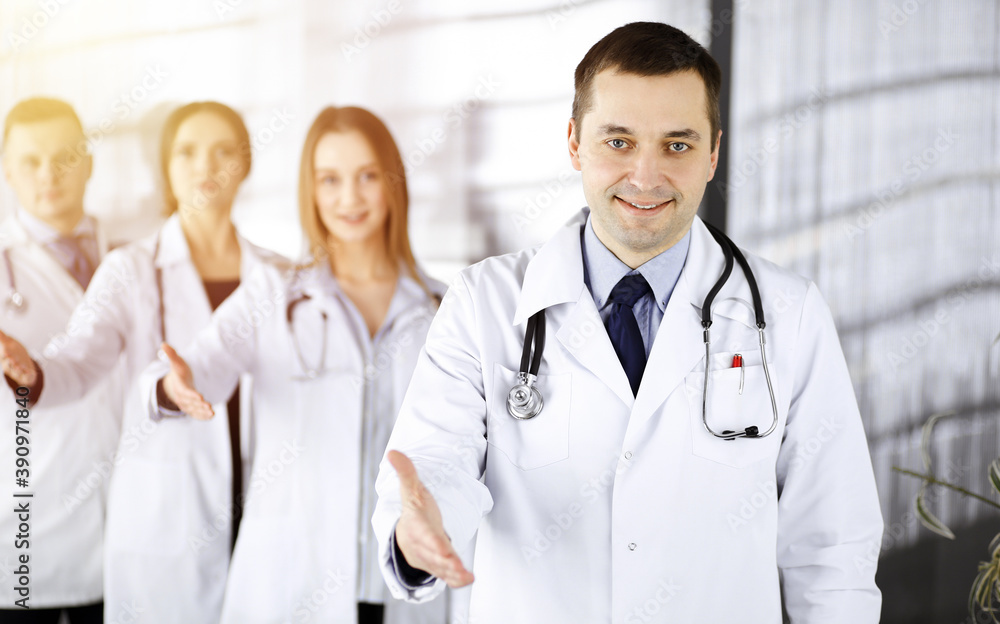 Fototapeta premium Team of friendly professional doctors are offering their helping hand for the people in a sunny clinic. Physicians are ready to help their patients. Best medicine concept nowadays