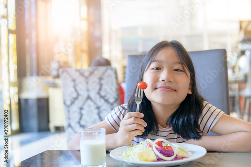 Asian cute little girl eating fresh tomato and salad on morning.