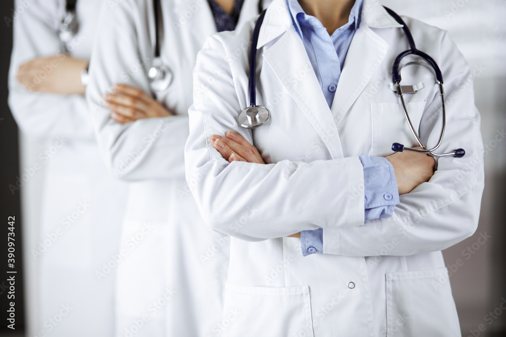 Group of modern doctors standing as a team with arms crossed in hospital office and ready to help patients. Medical help, insurance in health care, best disease treatment and medicine concept Group of modern doctors standing as a team with arms crossed in hospital office and ready to help patients. Medical help, insurance in health care, best disease treatment and medicine concept