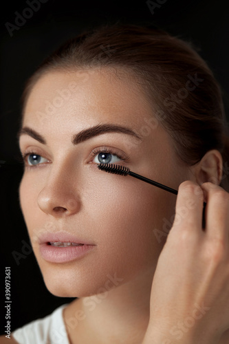 .Eyebrow makeup. Beautiful woman shaping brows with eyebrow brush closeup. Beauty girl model with professional makeup contouring eyebrows