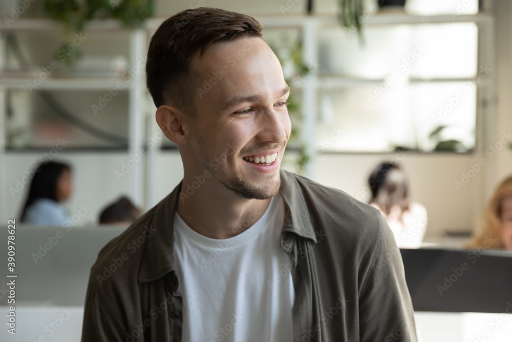 Obraz premium Modern employee. Confident positive young male office worker in informal wear smiling looking aside having good workday enjoying favorite job, happy man client satisfied with getting perfect service