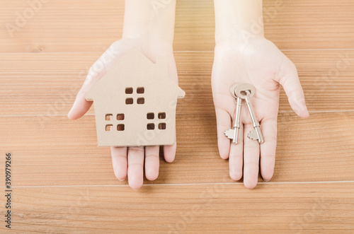 Lady hand with key of sweet home on wood background
