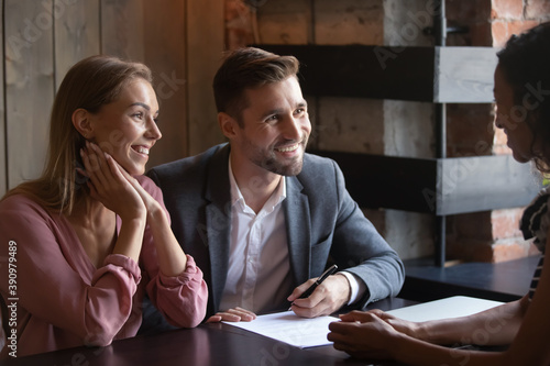 Satisfied customers. Happy millennial couple buyers renters tenants of apartment signing formal papers on meeting at cafe with agent seller lawyer, pleased young spouses becoming owners of new house photo