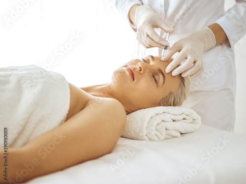 Beautician doctor hands doing beauty procedure to female face with syringe. Cosmetic medicine and surgery, beauty injections concept