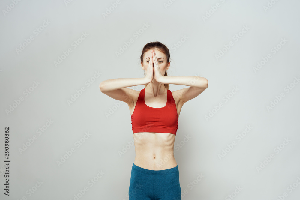 A woman in a red T-shirt on a light background is engaged in fitness gestures with her hands a slim figure A woman in a red T-shirt on a light background is engaged in fitness gestures with her hands a slim figure