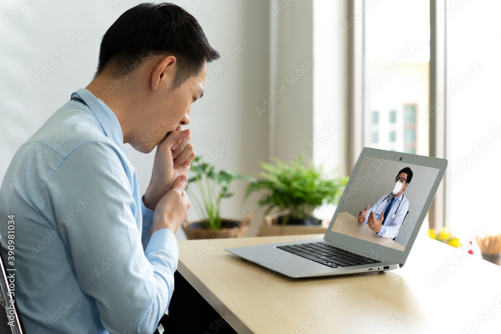 young businessman has sore throat from cold at office, so he consult asian doctor online via video call conference to ask for advice. telemedicine concept young businessman has sore throat from cold at office, so he consult asian doctor online via video call conference to ask for advice. telemedicine concept