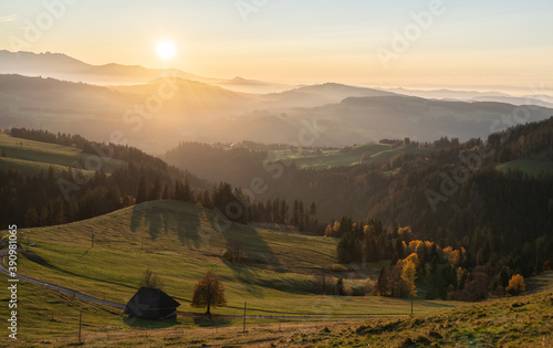 overview swiss landscape with hills forests mountains in warm color during sunset or sunrise and epic sky
