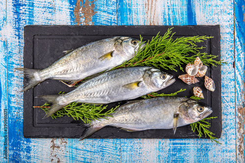 Raw fish (bluefish). Sea fish, blue fish and lemons together on wooden background. photo