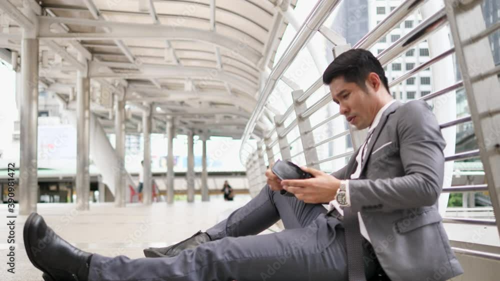 Asian businessman poor gesture because empty wallet no money while sitting outdoors near office building. Asian businessman poor gesture because empty wallet no money while sitting outdoors near office building.